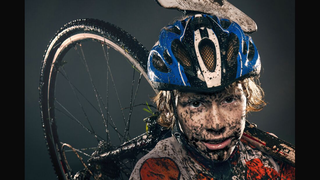 Mud splattered cyclist carrying bicycle