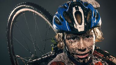 Mud splattered cyclist carrying bicycle